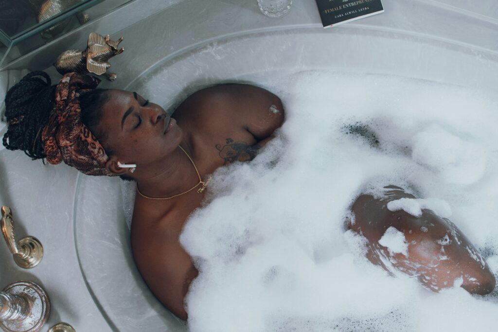 Woman in bubble bath with headphones practising self-care